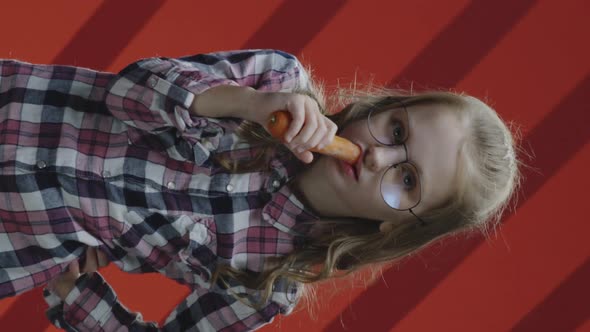 Girl Eating Carrot and Smiling at Camera