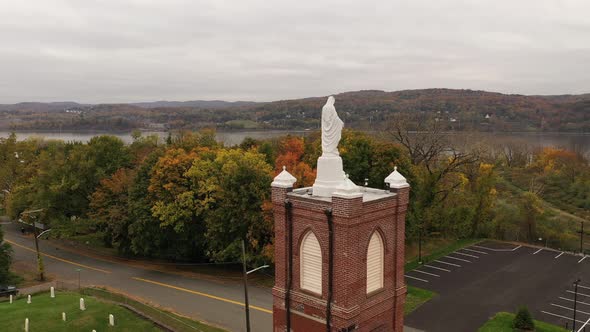 An aerial view of a statue of the Virgin Mary on top of a Catholic Church in upstate, NY. The drone