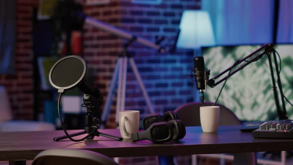 Closeup of Headphones and Professional Microphone on Empty Vlogger Desk Ready for Live Talk Show