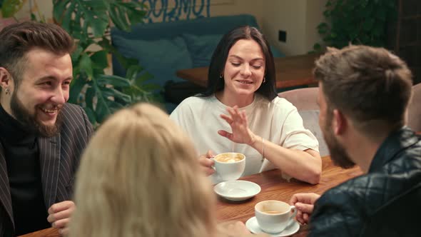 A white-skinned girl drinks filter coffee in a coffee shop in the company of cheerful friends.