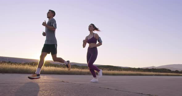 Tracking Slow Motion Shot of Sportive Couple Jogging Outdoors in the Morning Trail Running