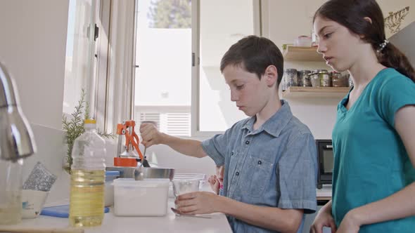 Kids preparing and mixing ingredients for pancakes in the kitchen