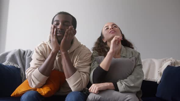 Excited Young Couple Relaxing At Home Sitting On Sofa Whilst Watching Sport On TV Together