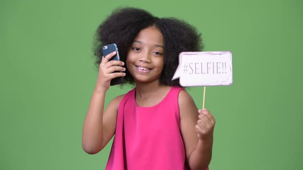 Young Cute African Girl with Afro Hair Taking Selfie with Paper Sign