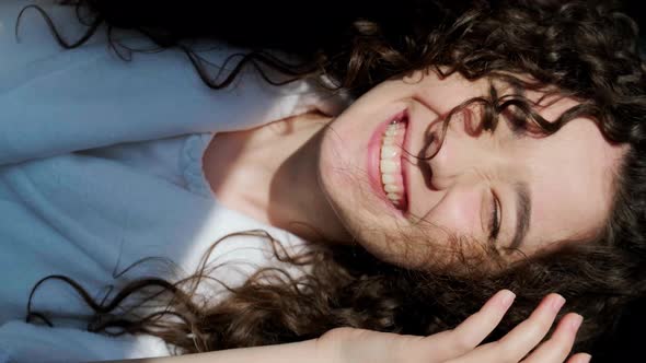 Portrait of Curly Haired Girl Looking at Camera with Charming Smile