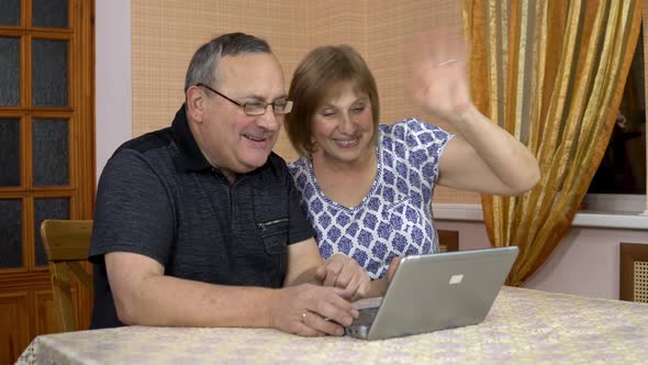 A Man and a Woman Communicate with Friends Via Video Communication Through a Laptop. An Old Man and