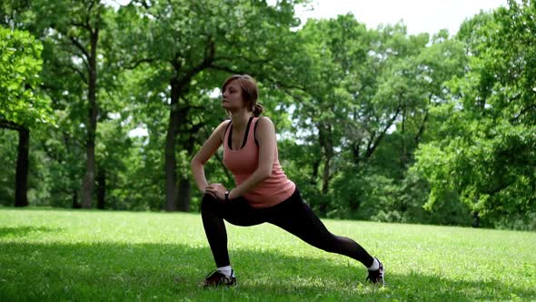 Girl Doing Squats in the Park on the Grass