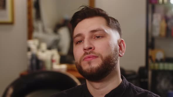 Handsome Young Happy Man Smiling After Haircut While Sitting in Chair in Barbershop