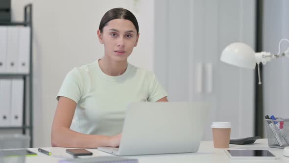 Young Latin Woman with Laptop Shaking Head in Denial