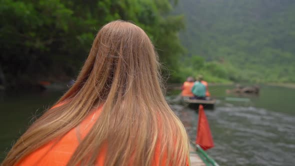 Slowmotion Shot of a Young Woman on a Boat Having a River Trip Among Spectacular Limestone Rocks in