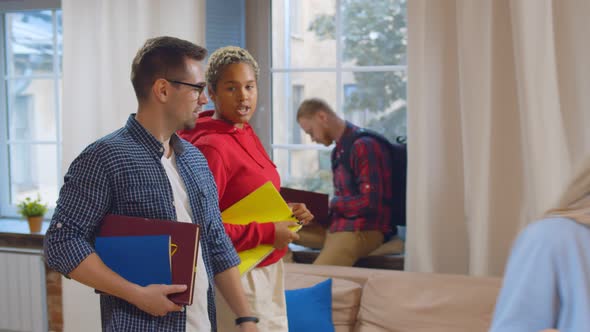 Diverse College Friends Discussing Project Walking in Common Living Room