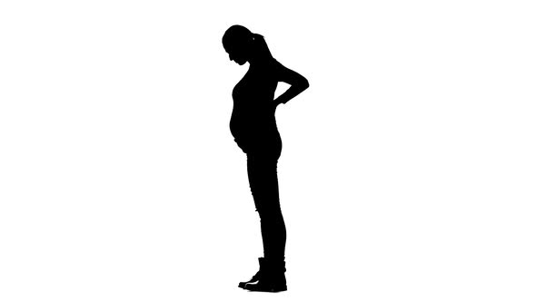 Pregnant Woman Is Standing and Stroking Her Stomach. Silhouette. White Background. Slow Motion