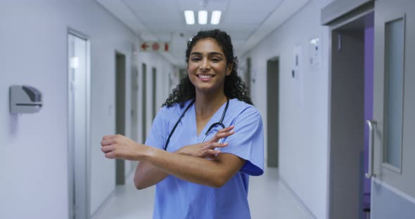 Portrait of smiling asian female doctor wearing scrubs standing in hospital corridor