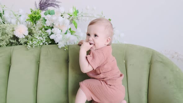 Little boy in a beige suit sits on a green sofa surrounded by beautiful flowers. Happy loving family