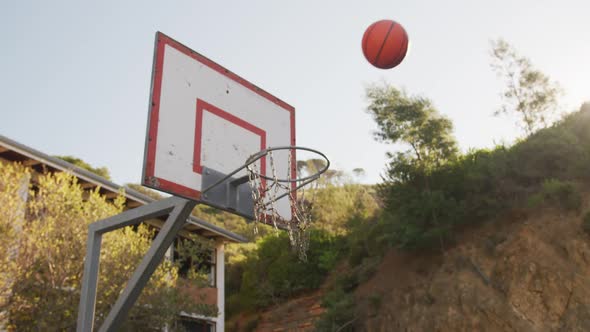 Basketball falling into a basket on a sunny day