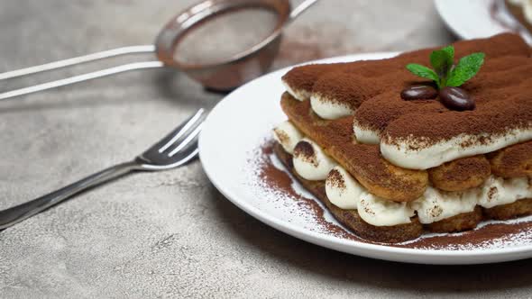 Two Portions of Classic Tiramisu Dessert on Ceramic Plate on Concrete Background