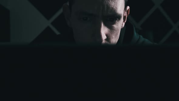 Young Man Looks at a Laptop Monitor Screen in a Dark Room at Home Male Read