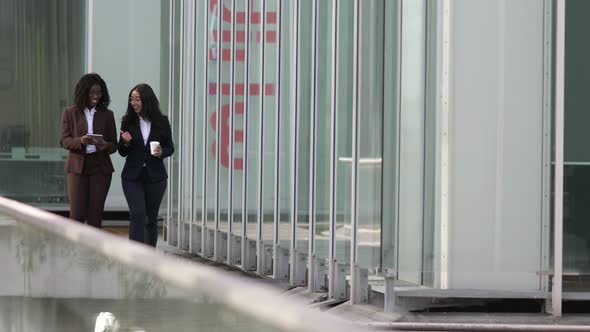 Smiling Businesswomen Looking at Tablet During Stroll