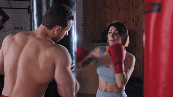 Boxing Training in the Gym Woman Boxer Training Her Punches on Punching Bag with Her Trainer Holding