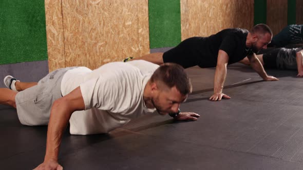 Strong Fit Athletic Men Doing Push Up Exercises in a Loft Style Industrial Gym