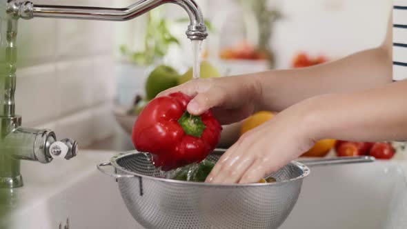 Handheld view of woman washing colorful peppers