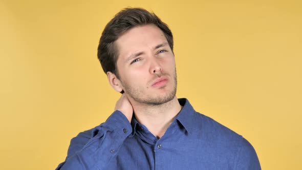 Casual Young Man with Neck Pain on Yellow Background