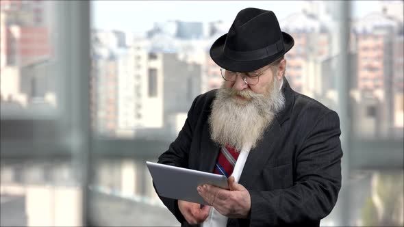 Senior Longbearded Man in Dark Suit Using Tablet Pc