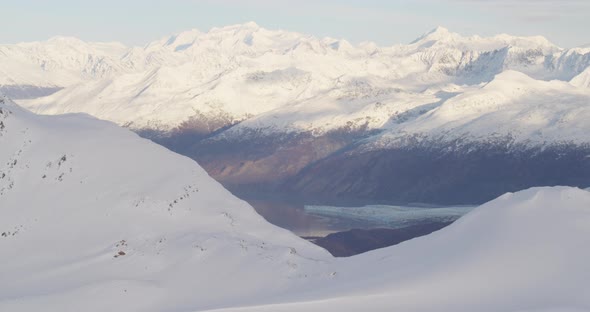 Aerial helicopter shot closeup across rippling glacier, tilt up from ice to Alaskan mountains, drone