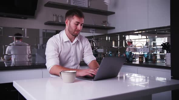 young man works at a laptop and drinks coffee