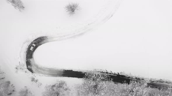 Cars Driving on Winter Country Road in Snowy Forest Aerial View From Drone