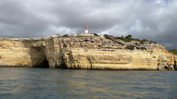 Lighthouse on a coastal seaside cliff on gloomy overcast day. View from sea