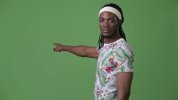 Young Handsome African Man with Dreadlocks Against Green Background