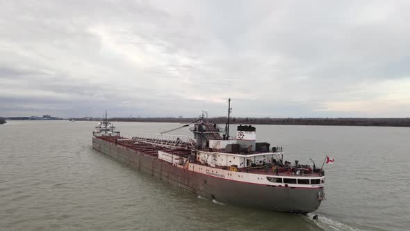 Old and rustic freighter with Canada flag on Detroit river, aerial view