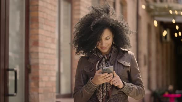 Portrait of Young African American Woman Texting on Her Smartphone