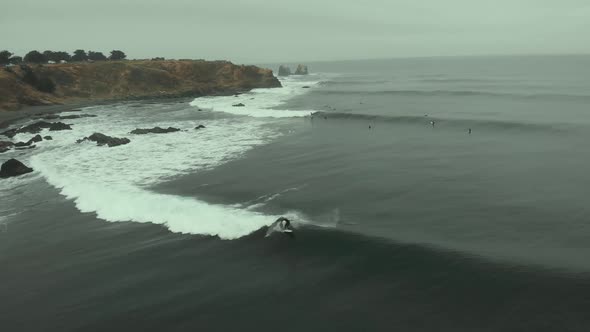 Surfer riding wave and falling on a dark day, Pichilemu, Chile