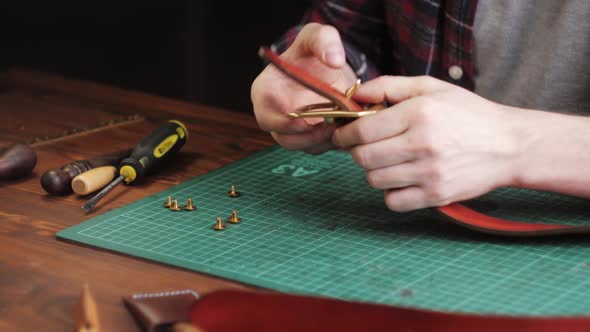 Man Tailor Cutting Artificial Leather with Ruler Closeup