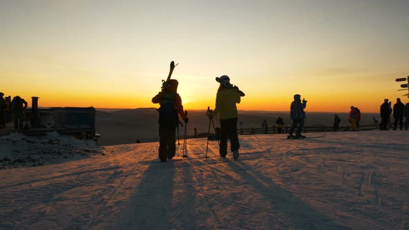 Silhouettes of People with Snowboards and Sticks on Slope