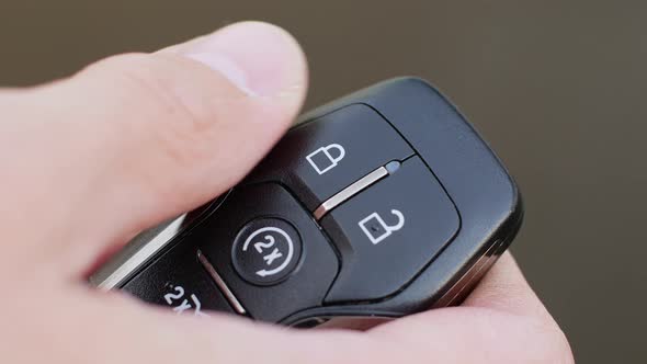 Man locks and unlocks car with key fob close-up on light gray background
