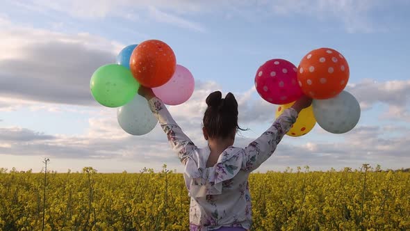 Girl in a Yellow Field Waving Her Hands with Balloons