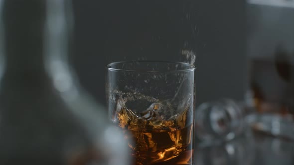 Ice is dropped into glass of whisky in slow motion; shot on Phantom Flex 4K at 1000 fps