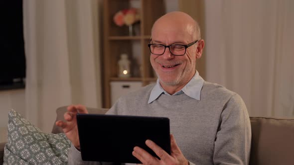 Old Man with Tablet Pc Having Video Call at Home