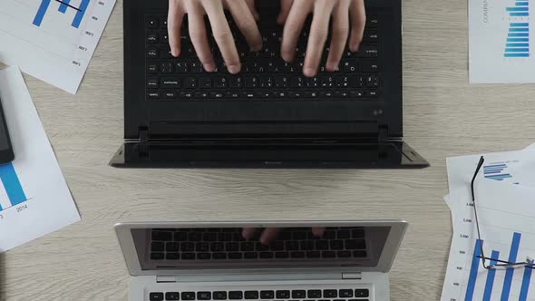 Two Office Workers Typing on Laptop Actively, Businessmen Having Fun at Work