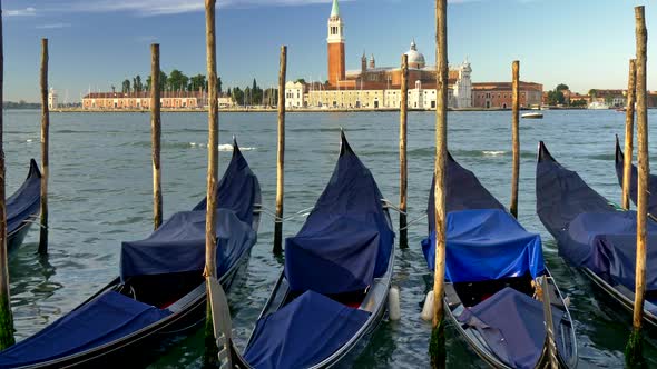 Venice, Italy. Docked Gondolas Covered with Blue Canvases Swaying in the Waves. St. Mark's Basilica