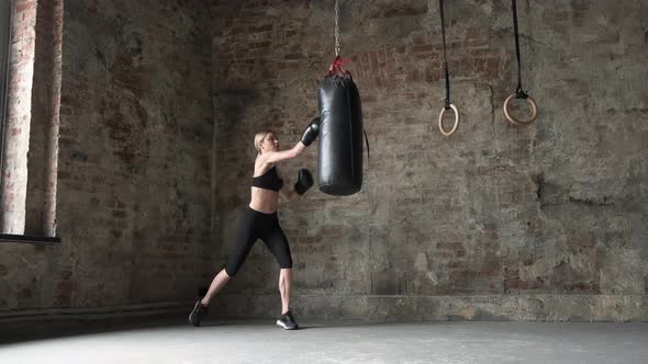 Taekwondo Professional Athlete Woman Kicks The Punches Bag In Gym. Athletic Kickboxing Woman.