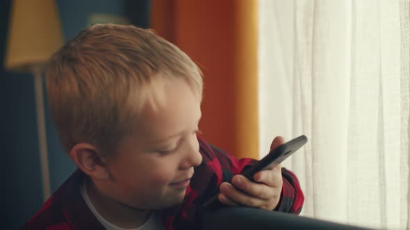 Smiling little boy is talking via video call sitting in a cozy, home-like atmosphere