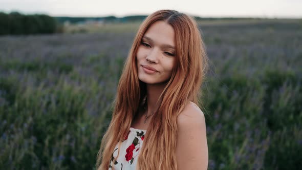 A Young Redhead Girl Walking Through Flowers on Flower Field. Beautiful Carefree Girl Enjoying