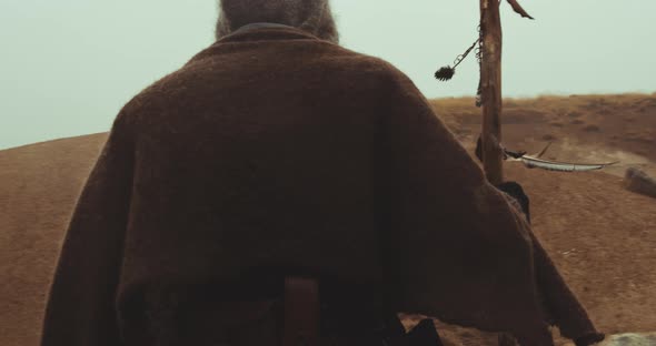 Hooded Man Walking Through Misty Landscape