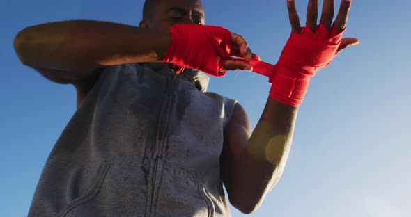 Focused african american man wrapping his hands, exercising outdoors