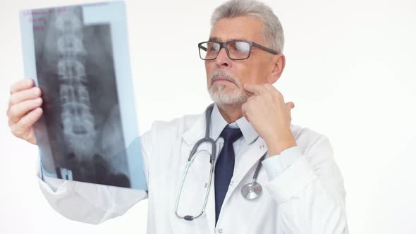 Adult Doctor Examines the Xray Image and Rubs Face and Corrects Glasses