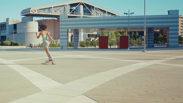 Beautiful young woman cruising around the city with her longboard.